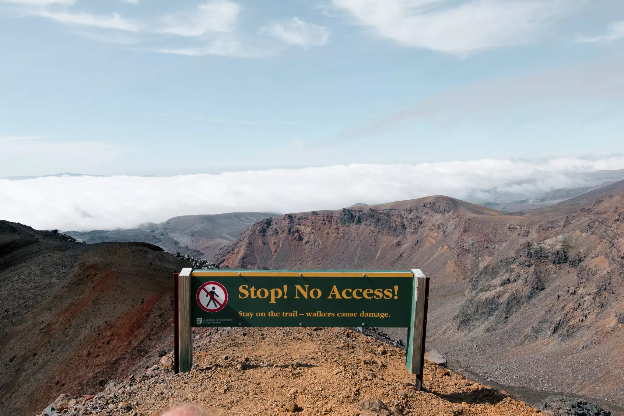 A sign that says "Stop! No Access" on the edge of a mountain ridge