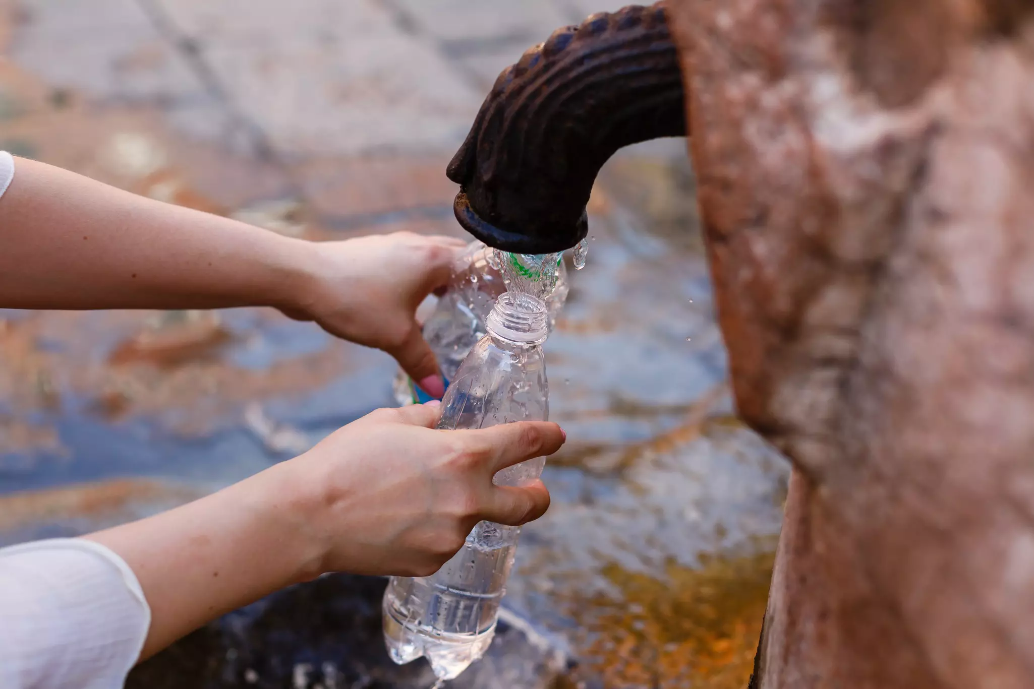 Filling a bottle with drinkable water in public fountain, Rome, Italy.