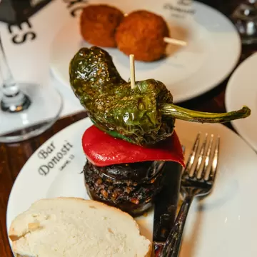 Small plates of individual portions of food arranged on a table. The plates have the name "Bar Donosti" on their rims