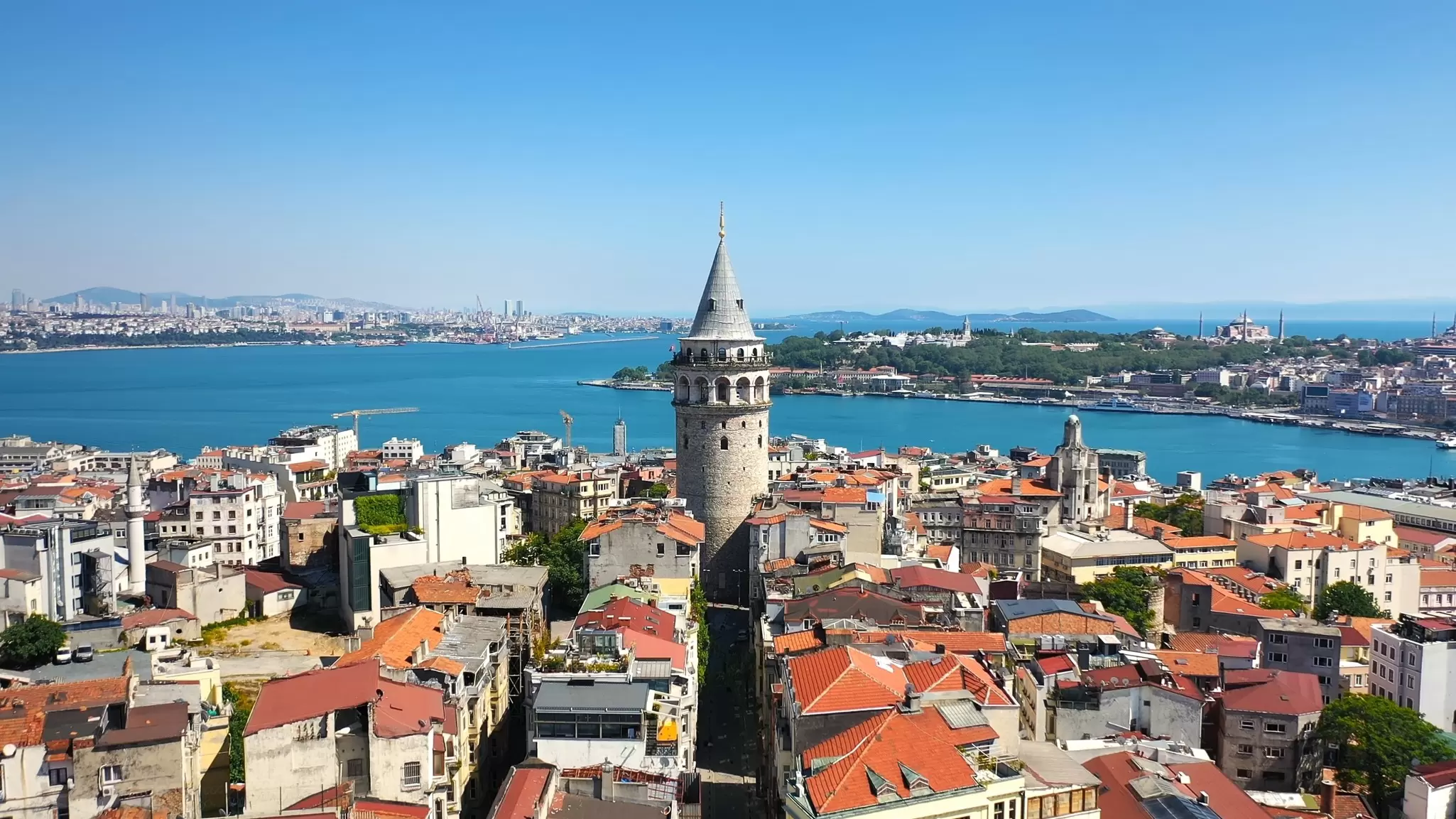 A conical tower at the top of a hill overlooks a wide river in Istanbul, Turkey