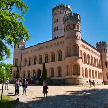 Pink hunting lodge with four crenellated corner towers and a tall central tower on a sunny day near Binz, Rügen
