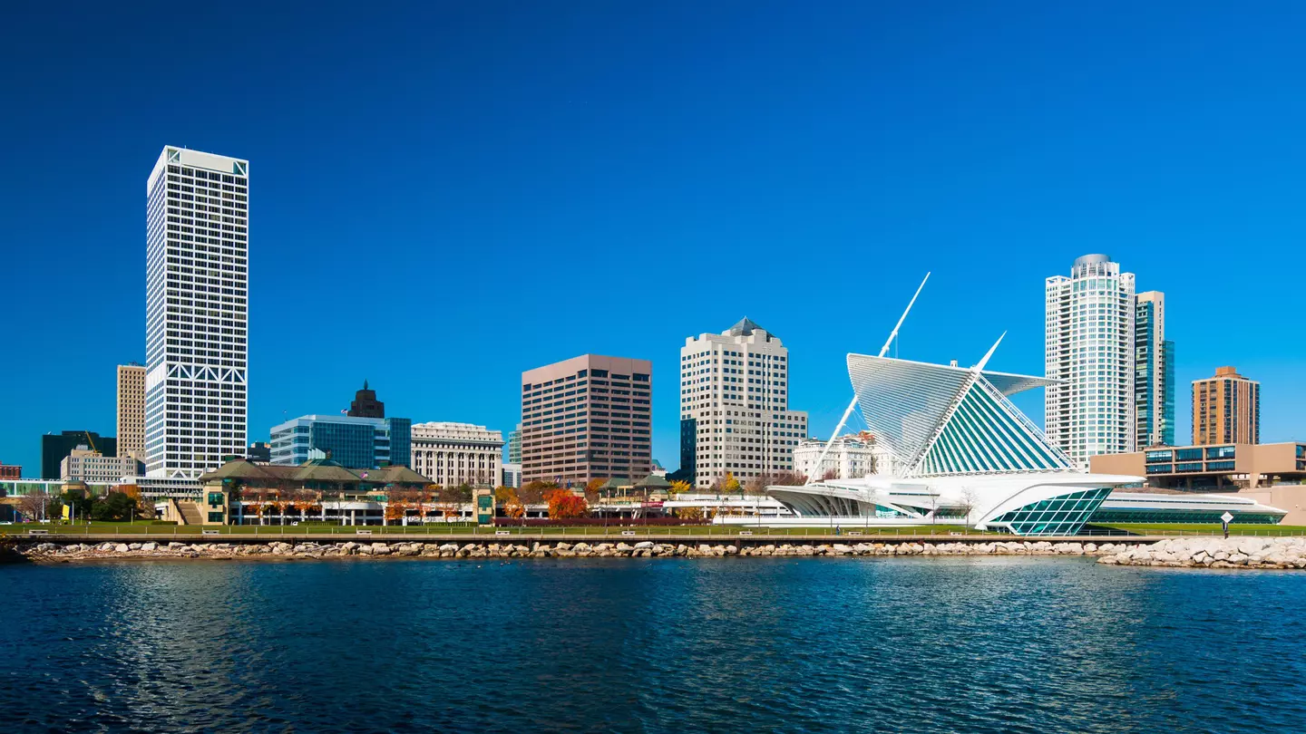 A lakefront city skyline with a modern art building to the right on a sunny day.