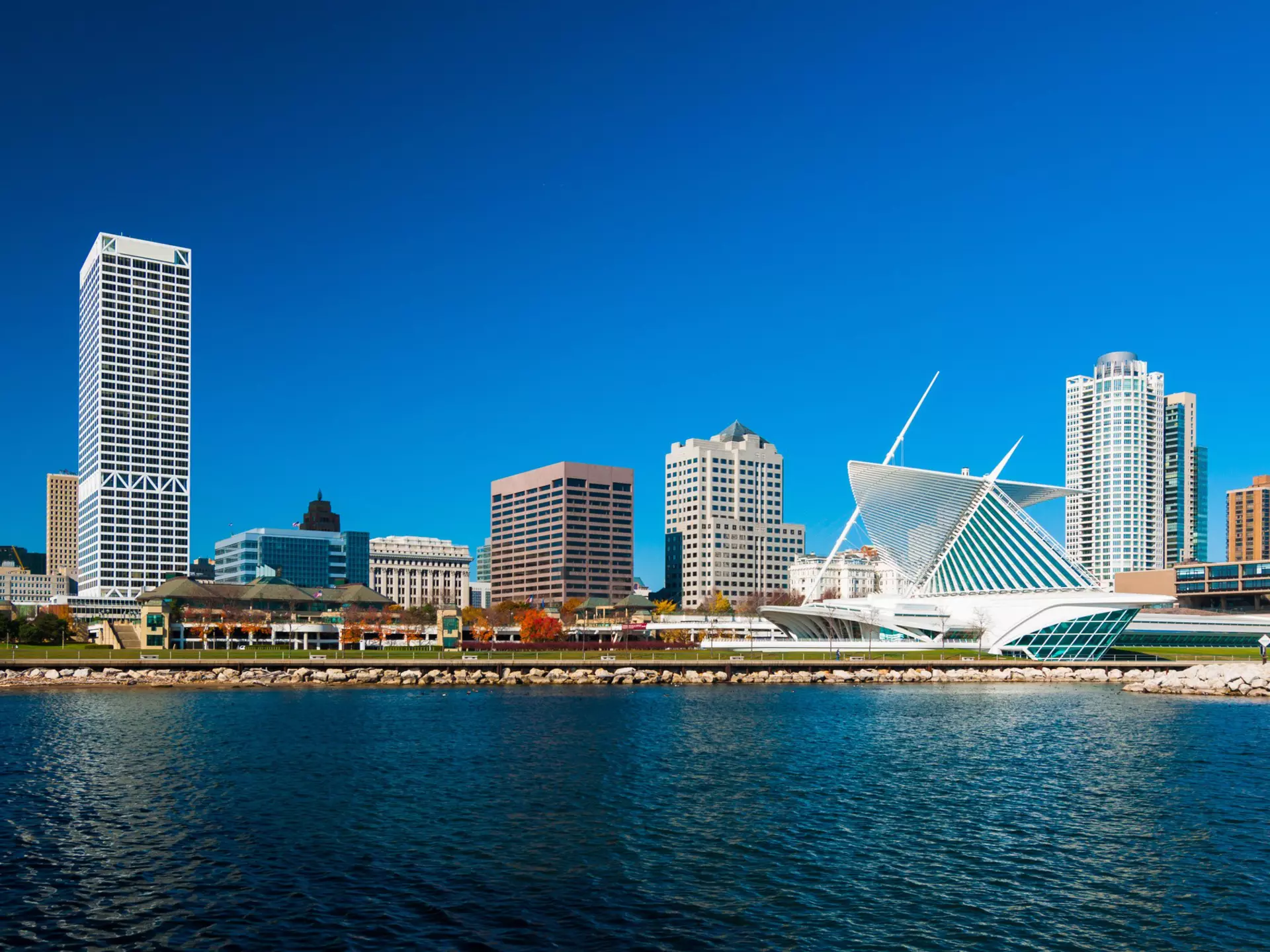 A lakefront city skyline with a modern art building to the right on a sunny day.