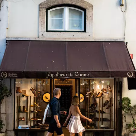 A man and woman walk past a shoe shop.