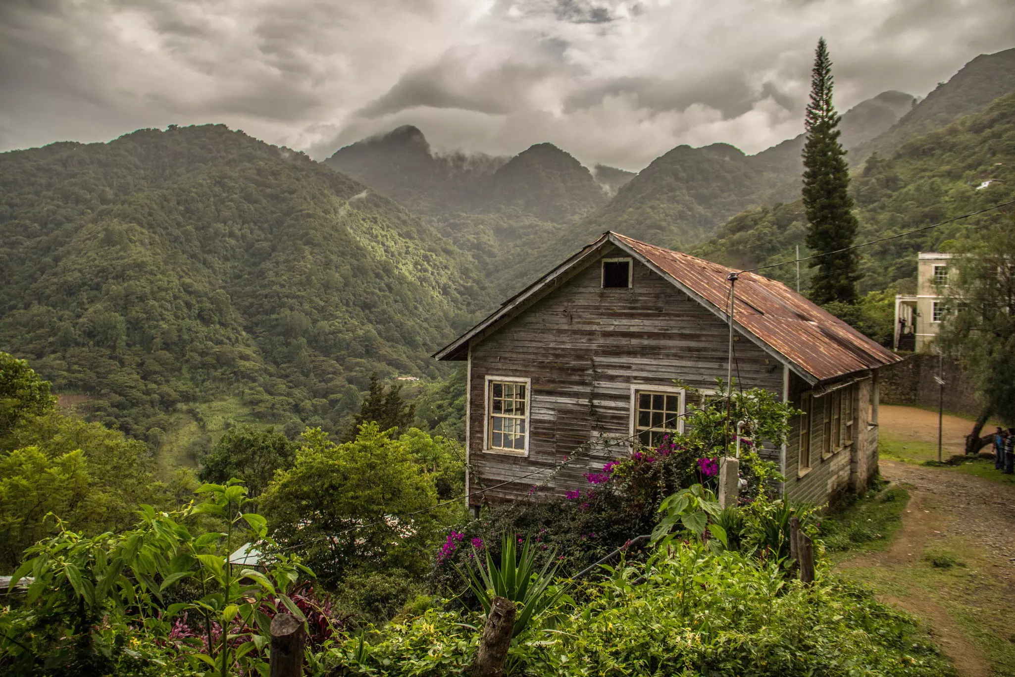 A wooden building at the edge of a mountain valley covered in forest.