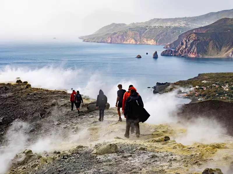Tourists walk on the crater of Vulcano Island near the sulphurous fumaroles. 