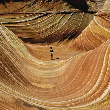 USA, Arizona/Utah border, woman walking across The Wave, rear view