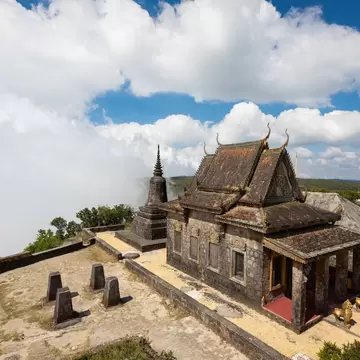 Wat Sampov Pram on Bokor Mountain, Cambodia: weathered stone temple and stupa on a clifftop terrace, cloud spilling past