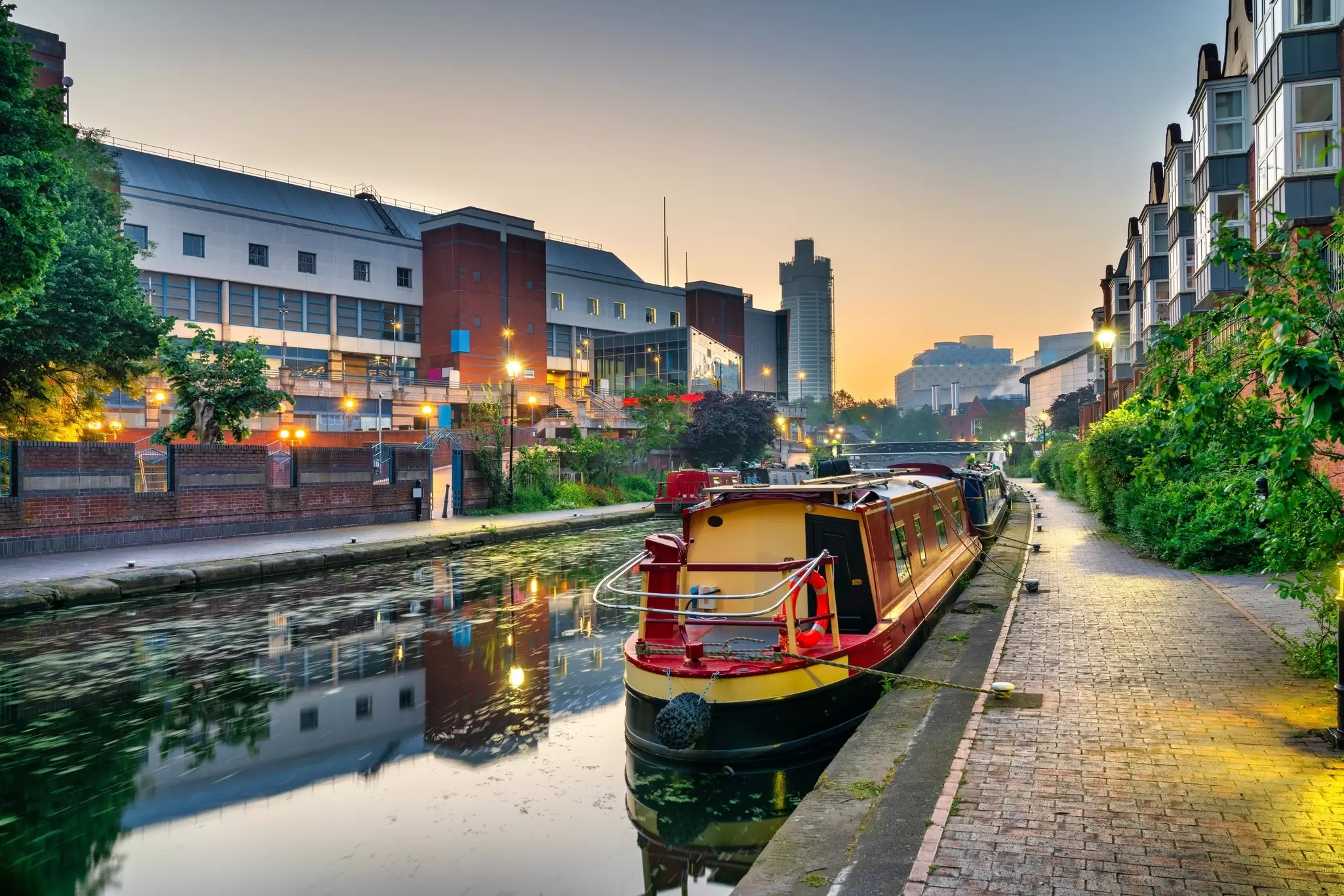 A narrowboat is moored in a canal in a dense urban neighborhood, Birmingham, UK