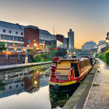 A narrowboat is moored in a canal in a dense urban neighborhood, Birmingham, UK