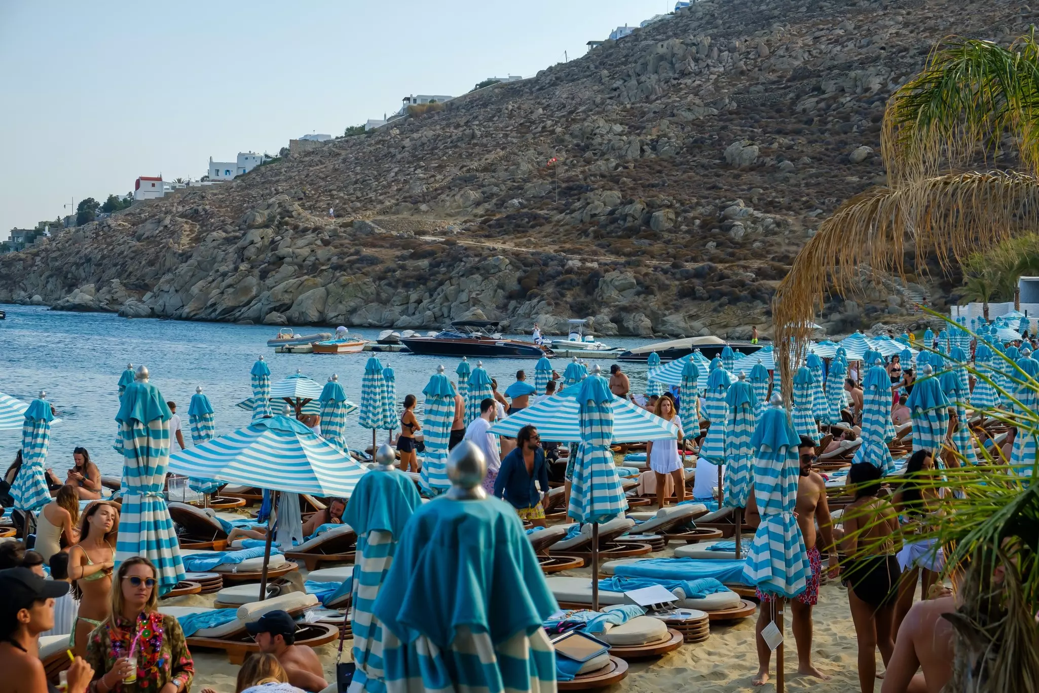 Blue-and-white striped sun beds and sun umbrellas at a crowded beach