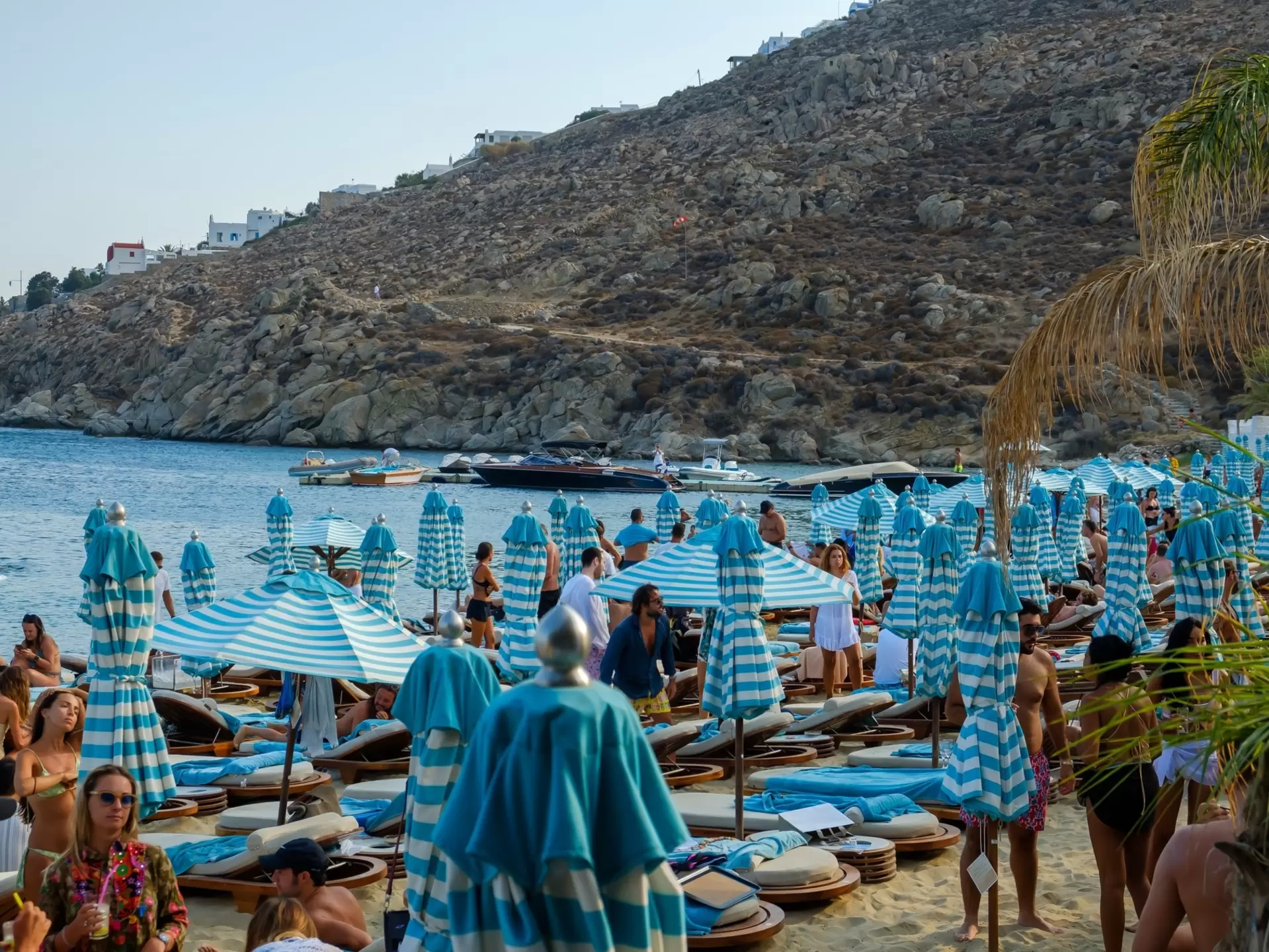 View of sun beds and sun umbrellas at the famous beach of Psarou in Mykonos, Greece. 
