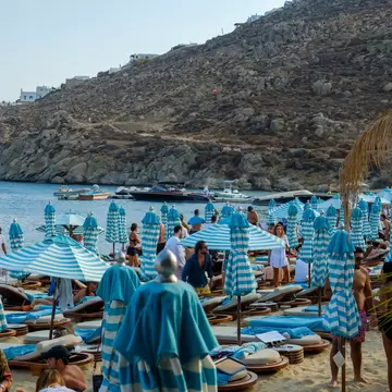 View of sun beds and sun umbrellas at the famous beach of Psarou in Mykonos, Greece. 