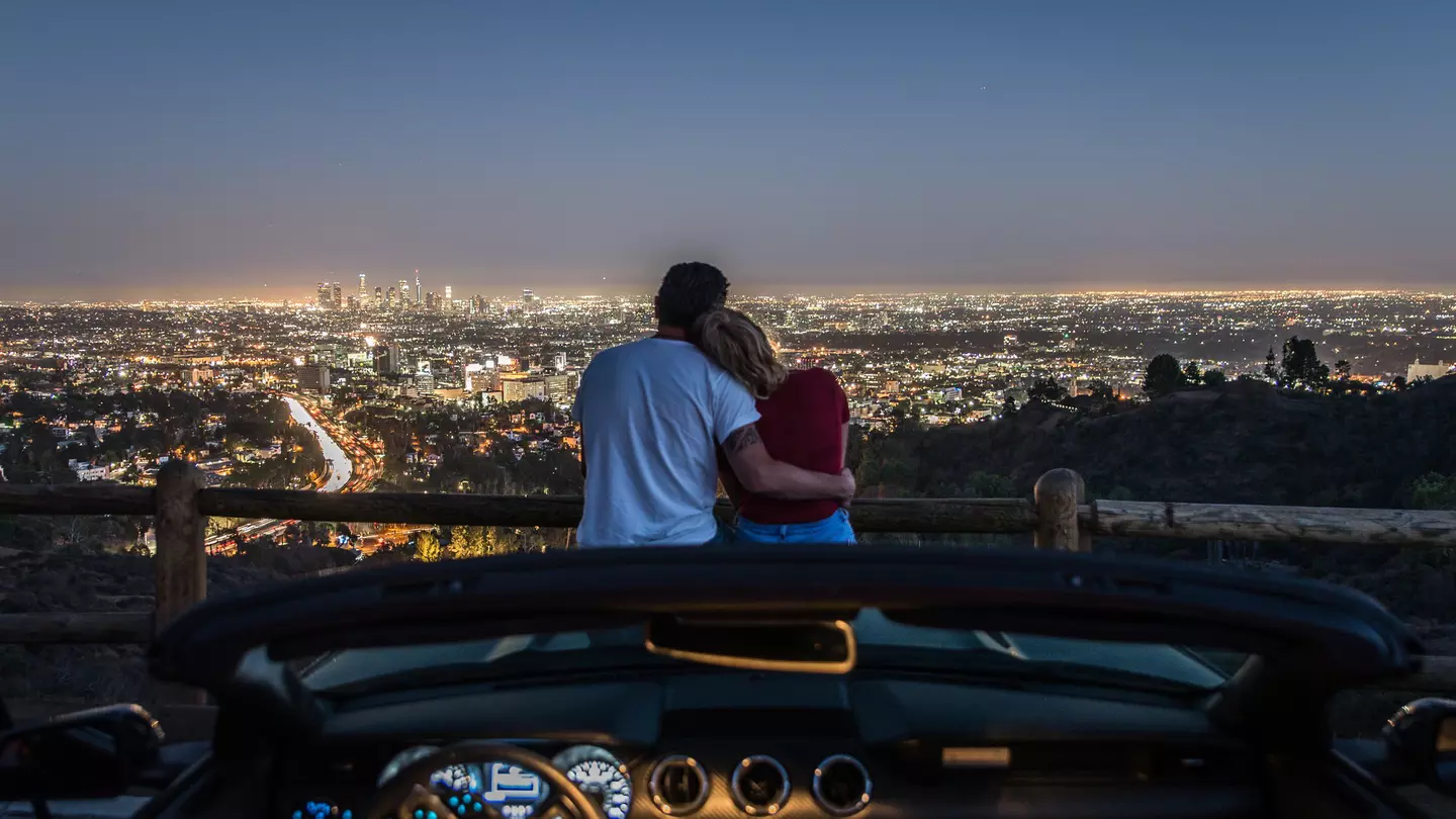 Couple,Enjoying,Skyline,View,From,Their,Car,In,The,Night.