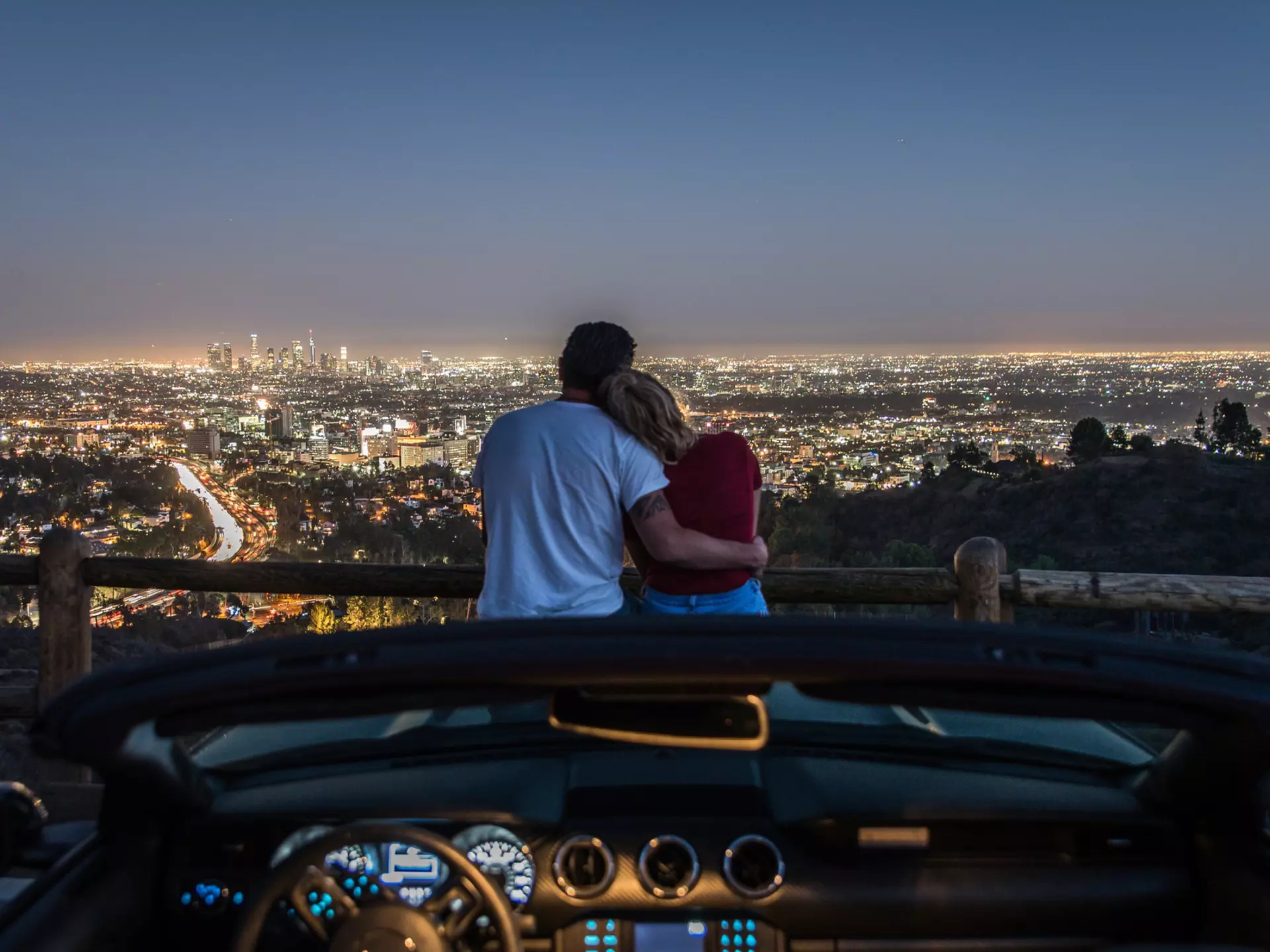 Couple,Enjoying,Skyline,View,From,Their,Car,In,The,Night.