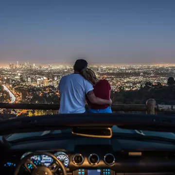 Couple,Enjoying,Skyline,View,From,Their,Car,In,The,Night.