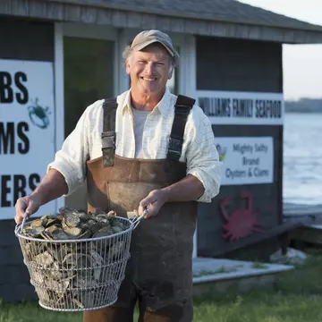 Caucasian fisherman holding basket of oysters in Northern Neck Virginia