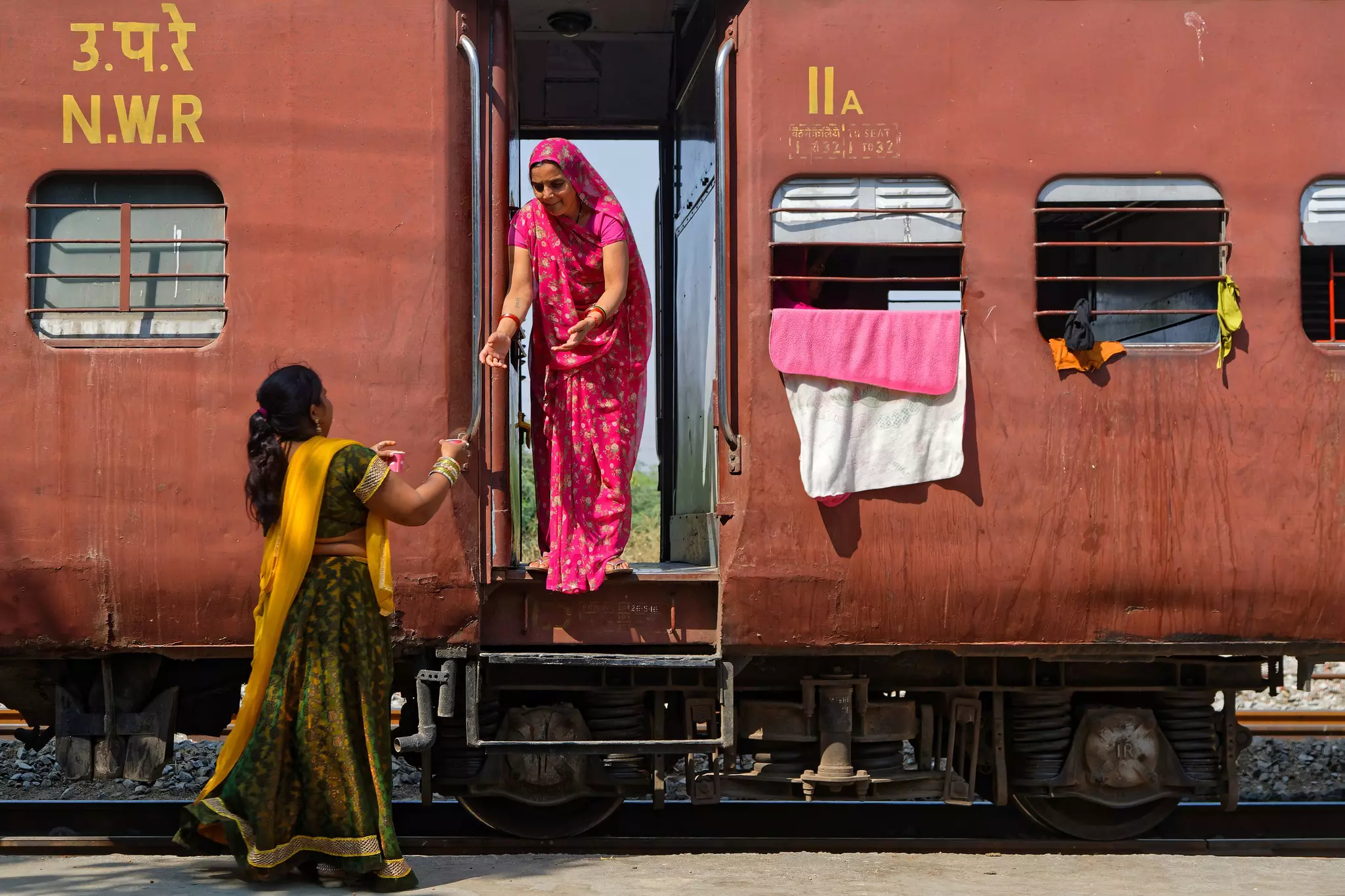 Women in colorful saris taking tea on a train in Rajasthan, India.