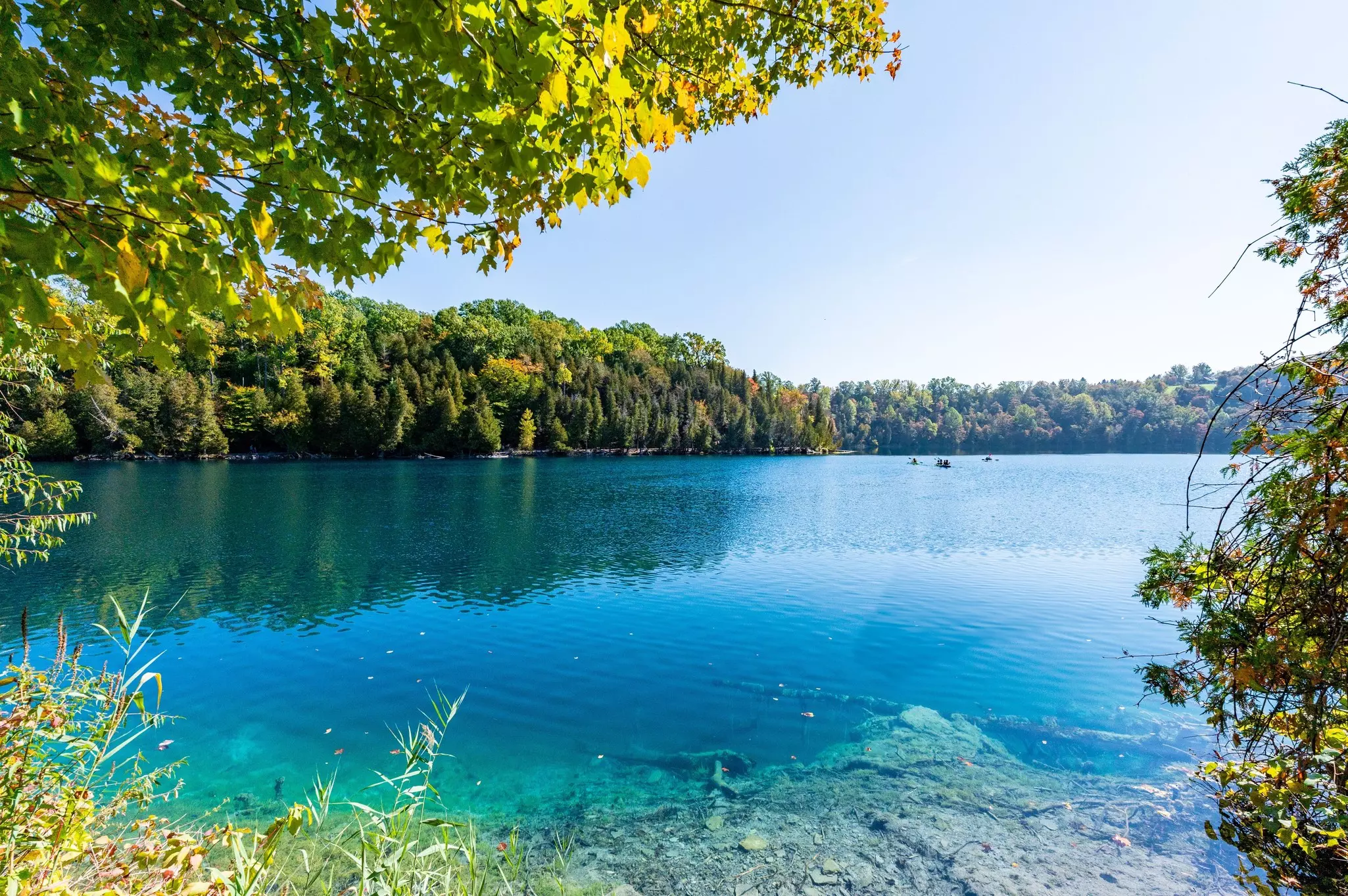 A clear turquoise lake with green trees along the shore.