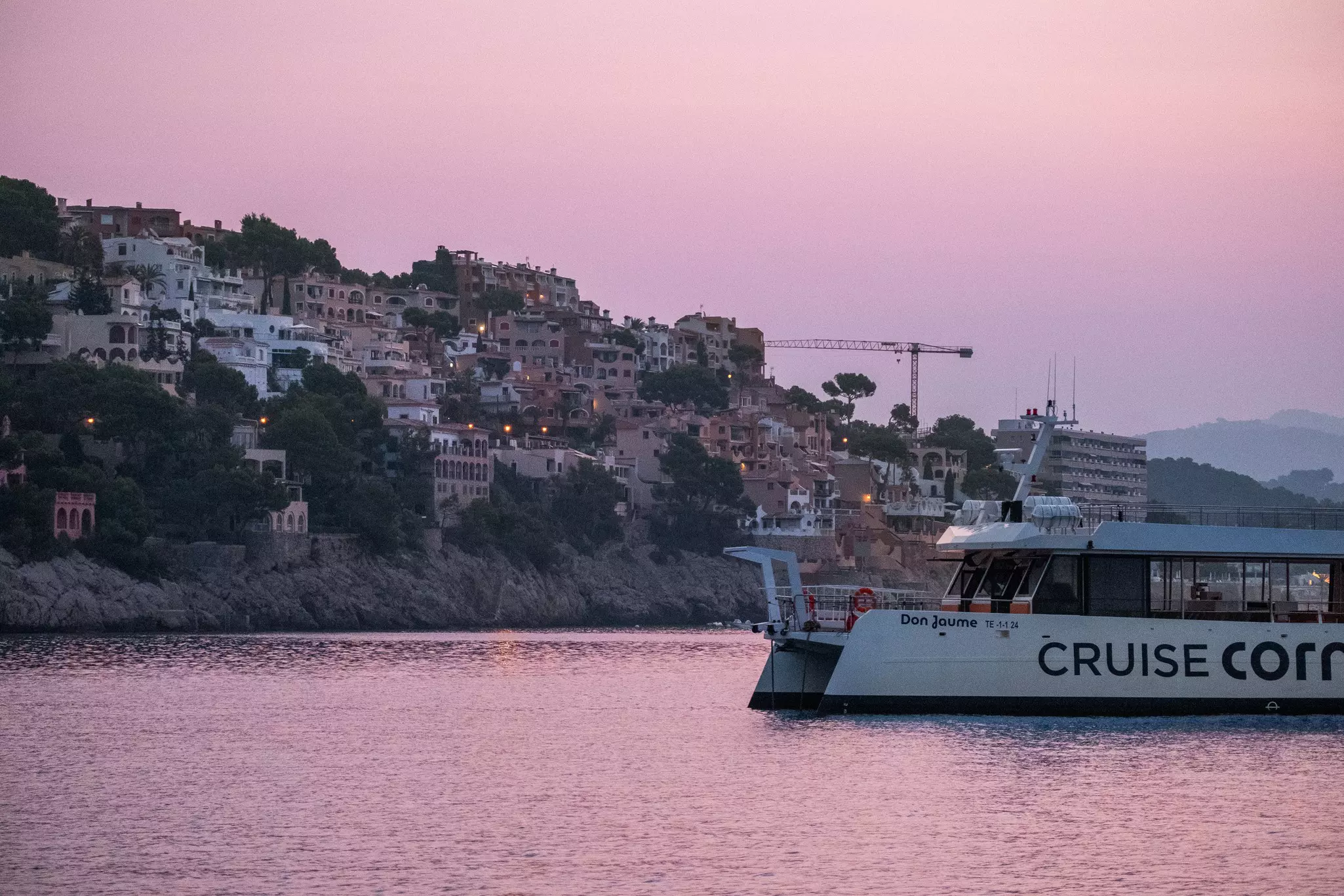 MALLORCA, SPAIN, AUGUST 2024..A ferry boat cruises along the coastline at dusk near a hillside village in Mallorca..Felipe Santibañez for Lonely Planet.
BIT 2025