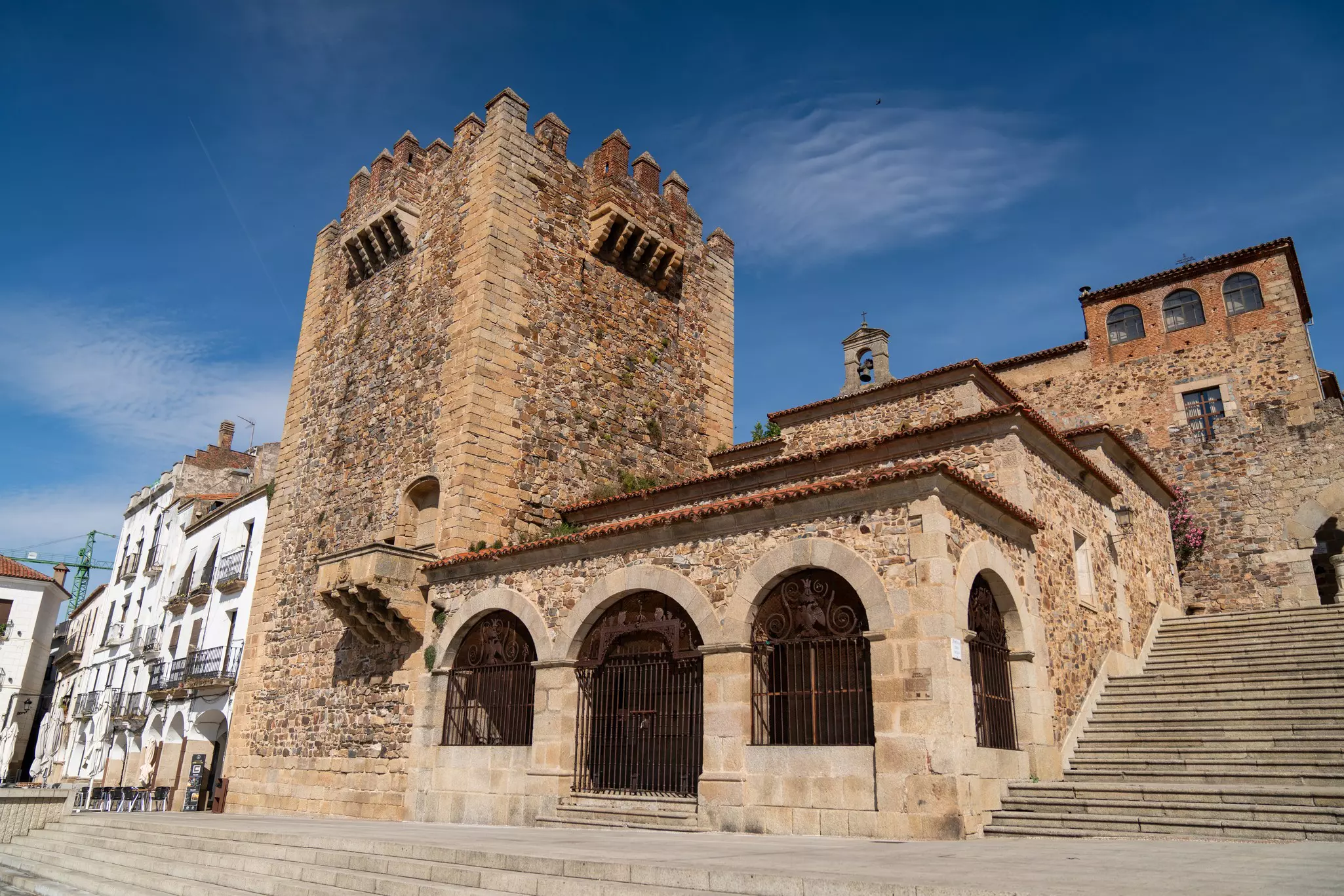 Brick and stone tower with stone stairs in front and to the side on a sunny day.