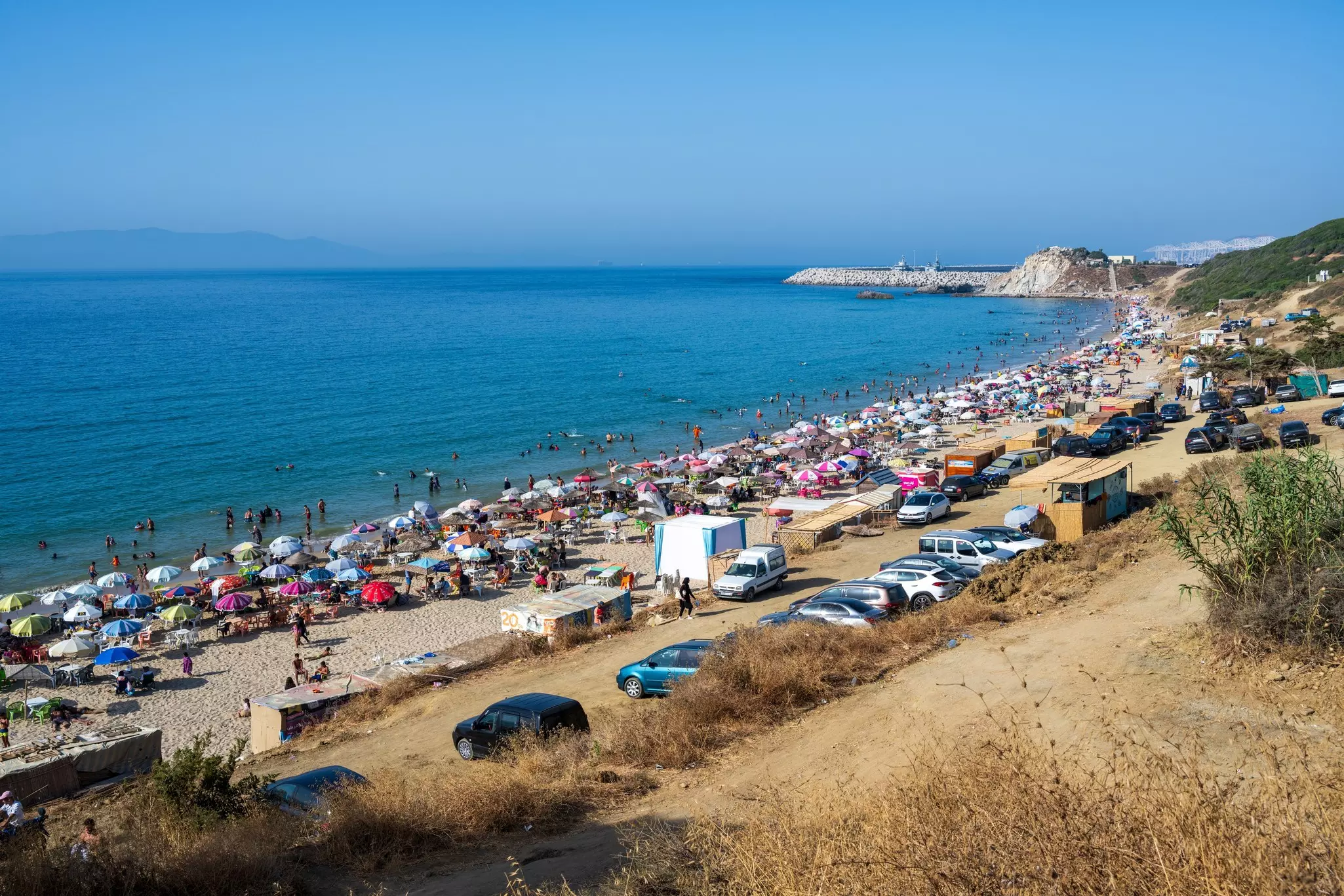 Beach on the Mediterranean coast near Tangier, Morocco. Moroccan people bathing, summer, holydays. Blue sky, coast, landscape,.