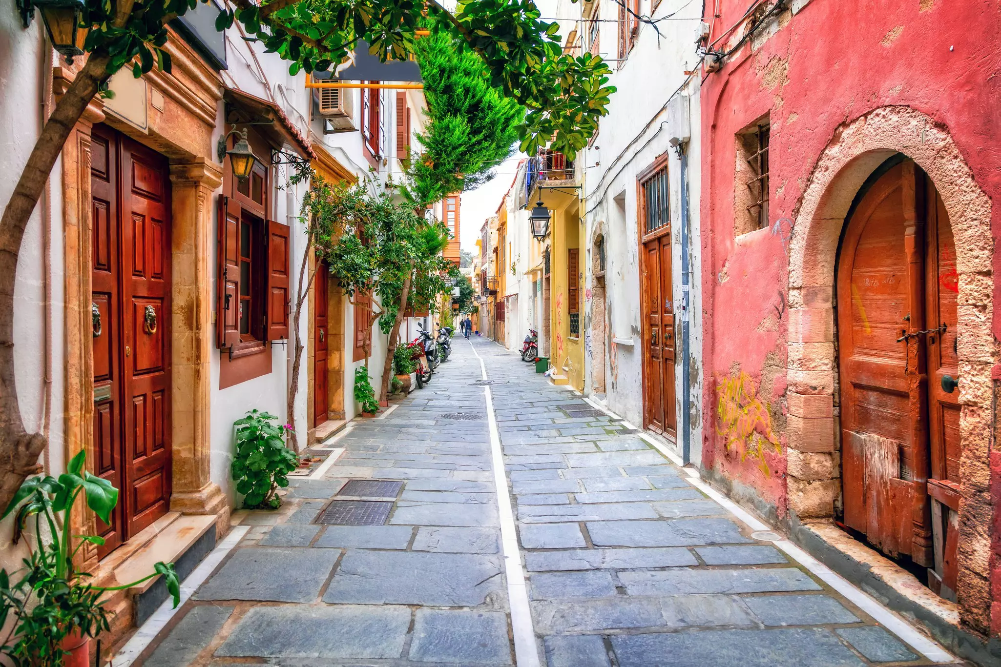A narrow alley is lined old stone buildings painted in bright colors, Rethymno, Crete