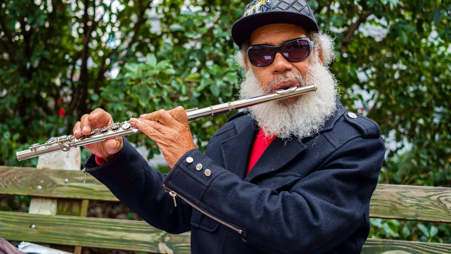 A musician plays the flute outside in a leafy square in Savannah's historic district