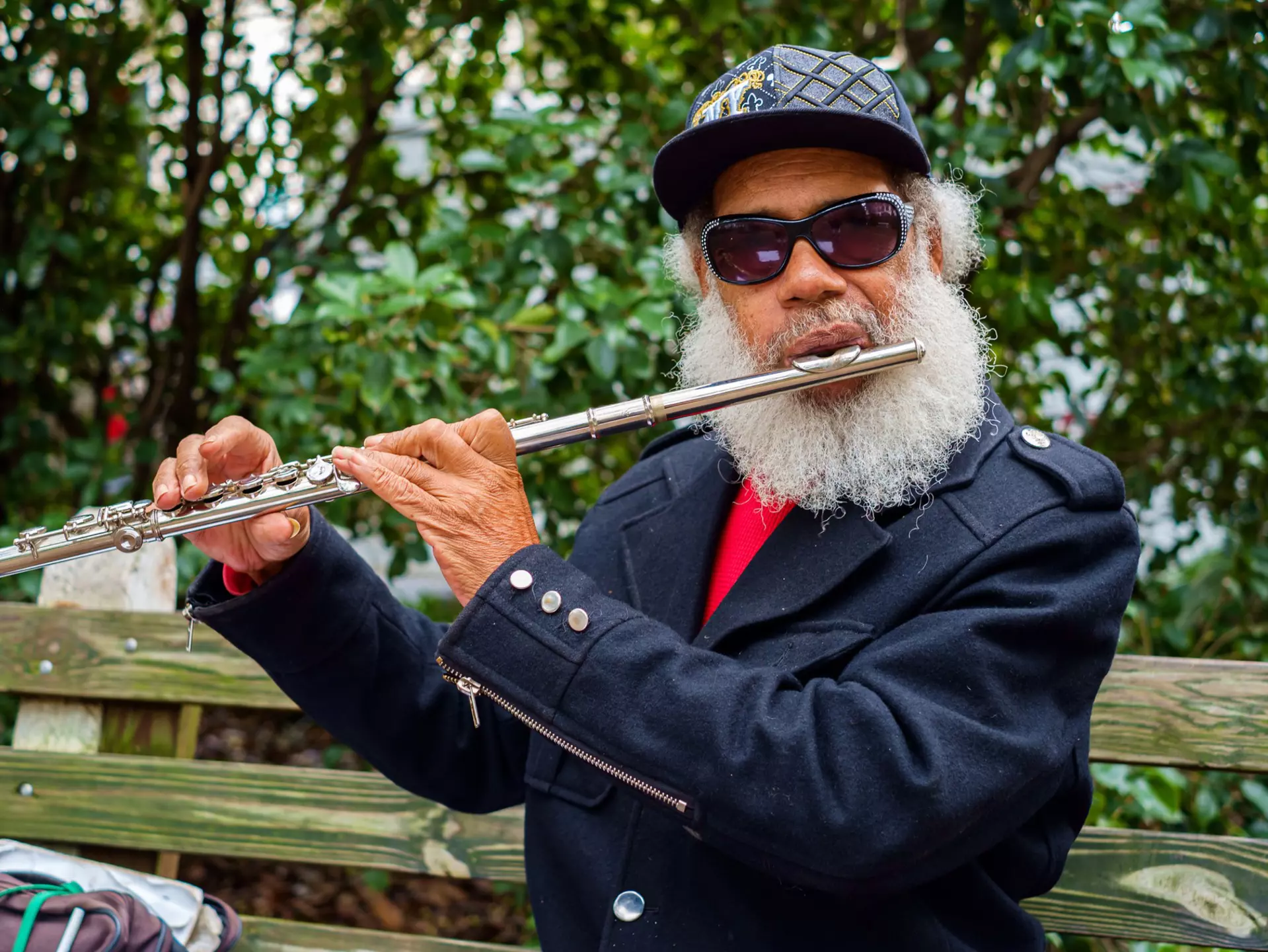 A musician plays the flute outside in a leafy square in Savannah's historic district