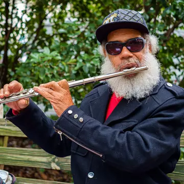 A musician plays the flute outside in a leafy square in Savannah's historic district