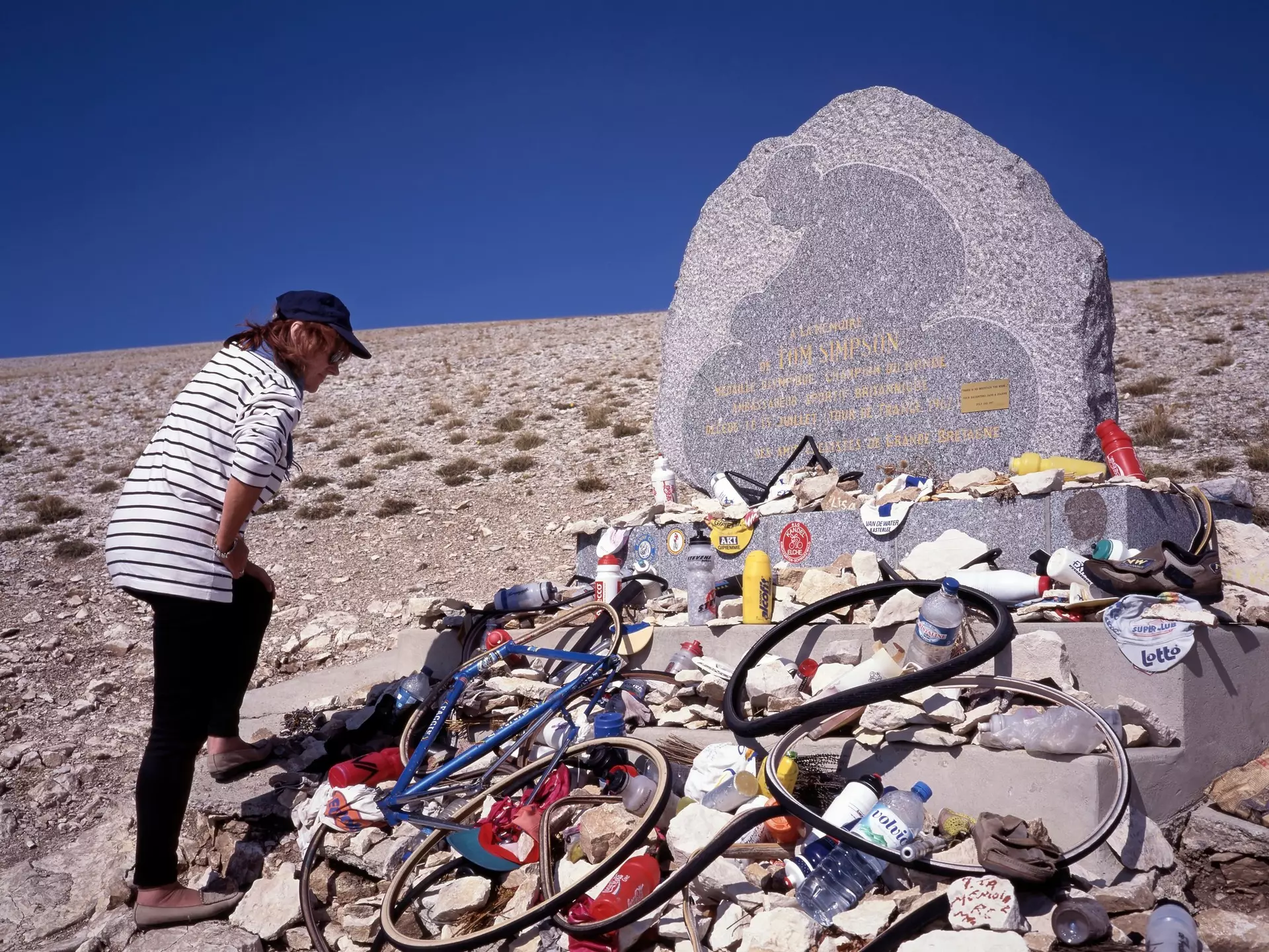 MONT VENTOUX, FRANCE- SEPTEMBER 15, 2020: A fan looking at the objects left by cyclists on the Tom Simpson memorial stone. He dead on the Tour de France to the Mont Ventoux, License Type: media, Download Time: 2025-10-15T00:31:44.000Z, User: hannahblackie10, Editorial: true, purchase_order: 56530 - Guidebooks, job: Global Publishing WIP, client: Experience Provence & the Cote D'Azur 2, other: Hannah Blackie