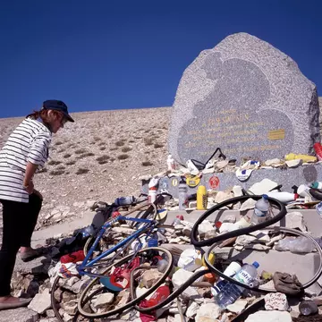 MONT VENTOUX, FRANCE- SEPTEMBER 15, 2020: A fan looking at the objects left by cyclists on the Tom Simpson memorial stone. He dead on the Tour de France to the Mont Ventoux, License Type: media, Download Time: 2025-10-15T00:31:44.000Z, User: hannahblackie10, Editorial: true, purchase_order: 56530 - Guidebooks, job: Global Publishing WIP, client: Experience Provence & the Cote D'Azur 2, other: Hannah Blackie
