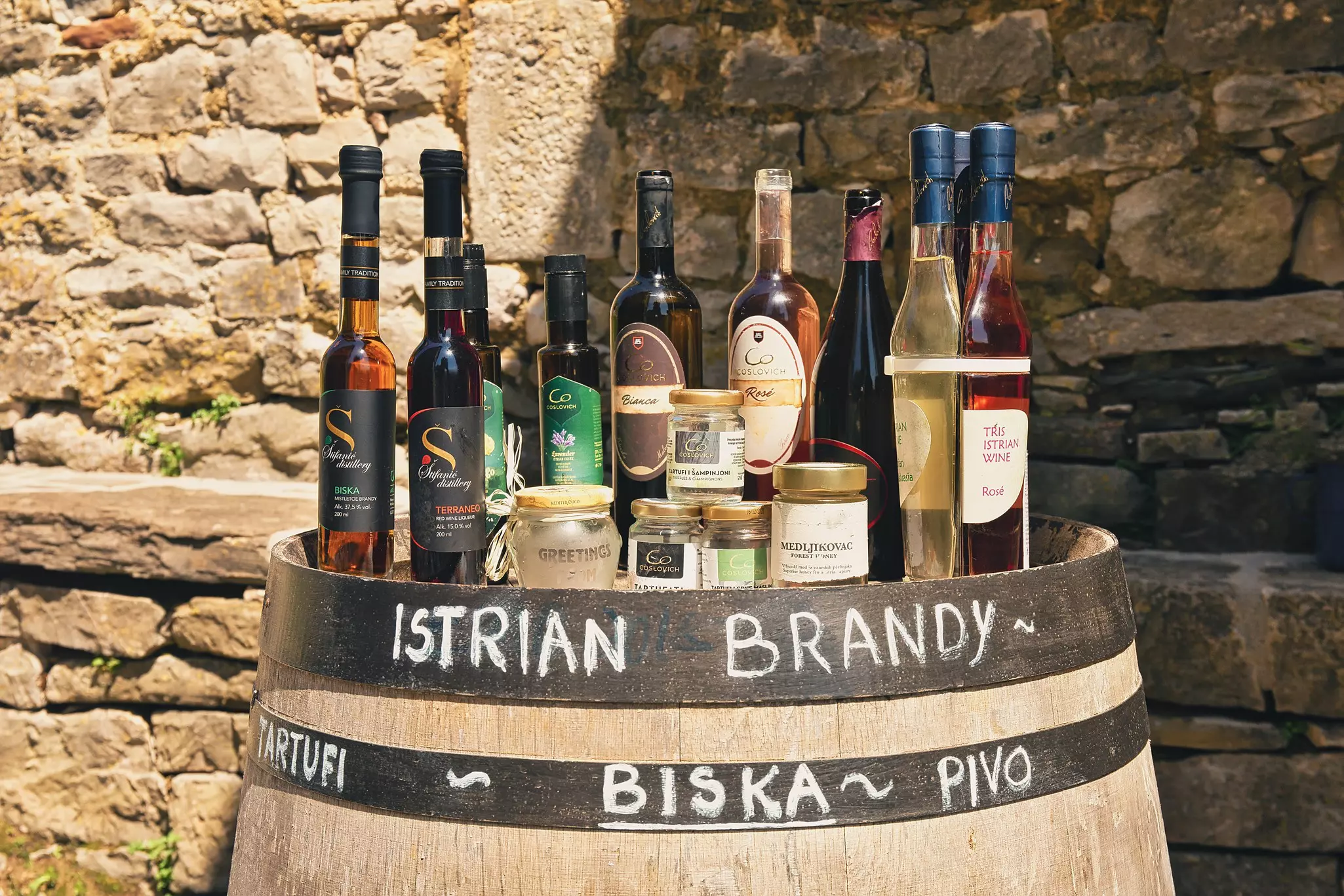 Several bottles of brandy and other items sit on top of a barrel; "Istrian brandy" is written on the barrel.