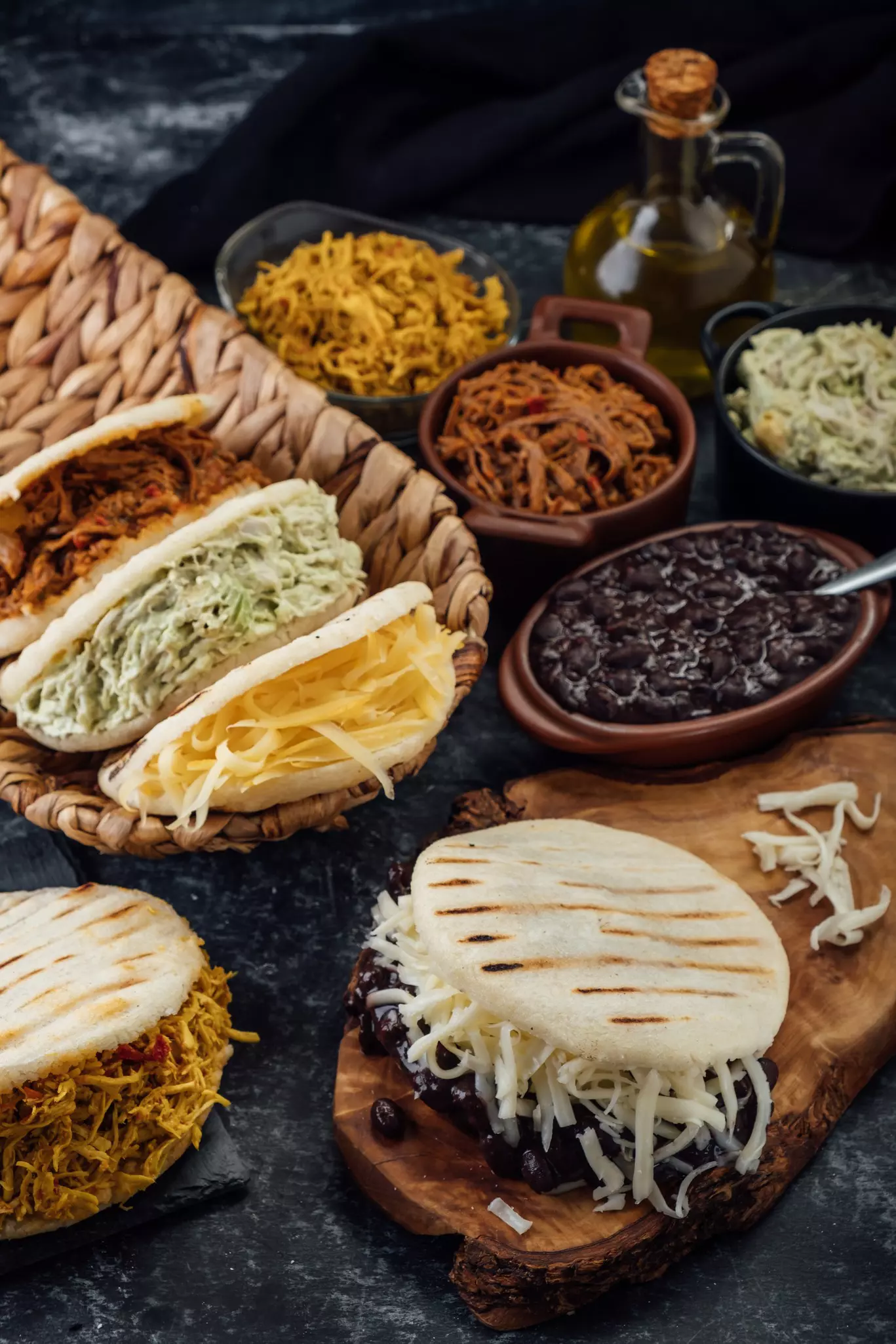 A woman wearing a red top, black apron and white headscarf squeezes milk into a plastic bowl from coconut shavings