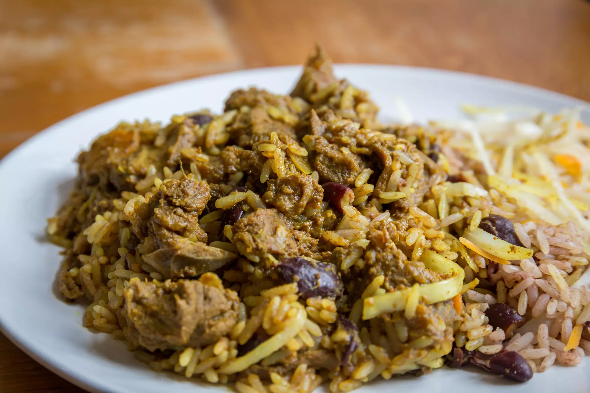 A dish of curried meat, rice and black beans.