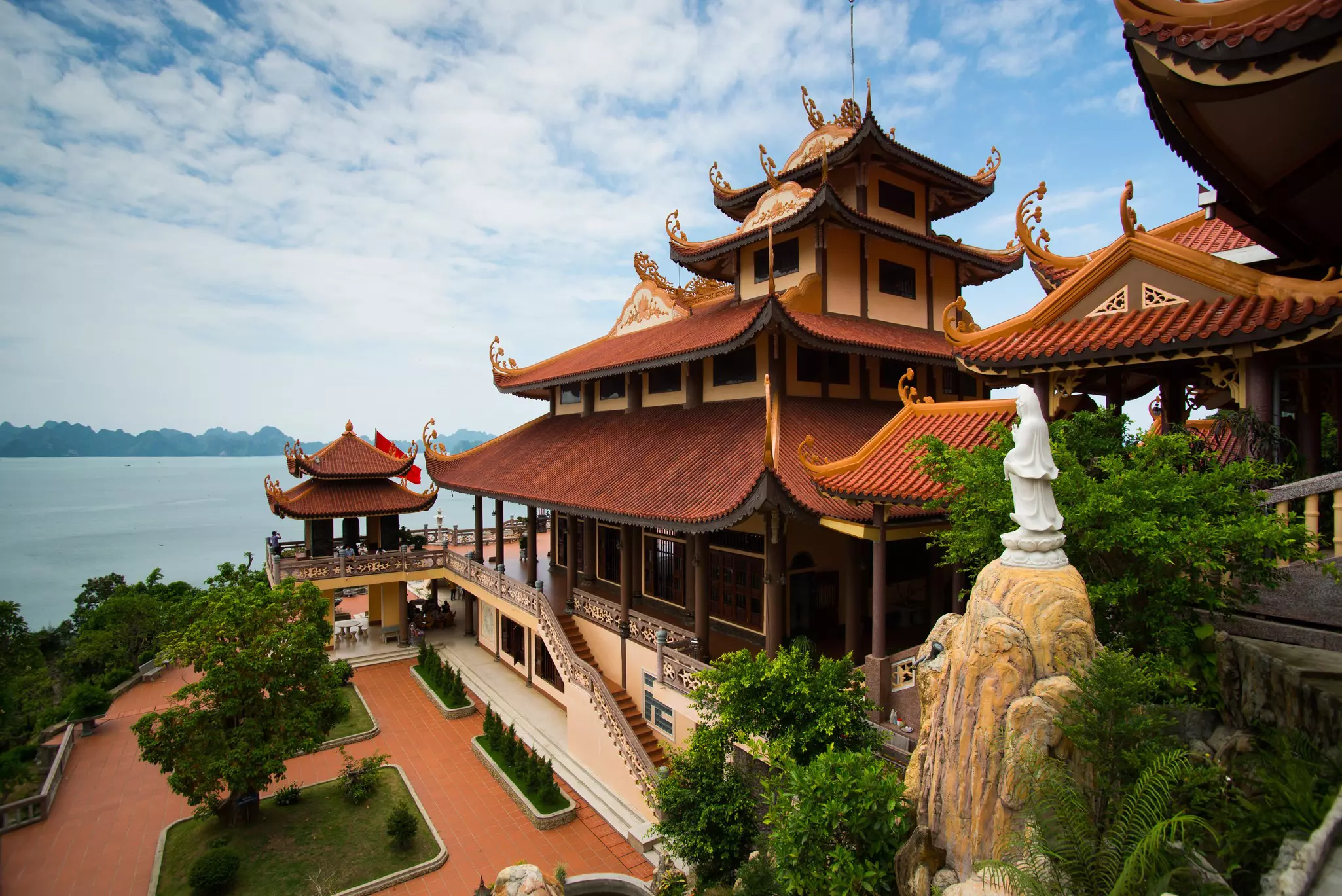 The multilevel roofs of several structures at a temple complex by a bay in Vietnam.