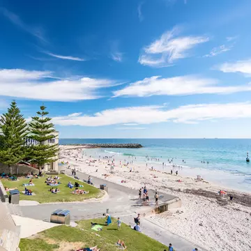 A sandy beach with people playing in the surf.