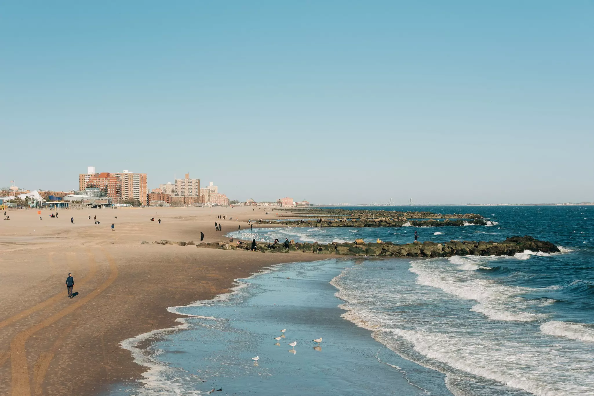 A beach with people dotting the shore and tall buidlings in the distance