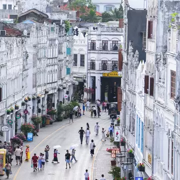 A busy city street lined with neat rows of houses: Haikou in Hainan, China
