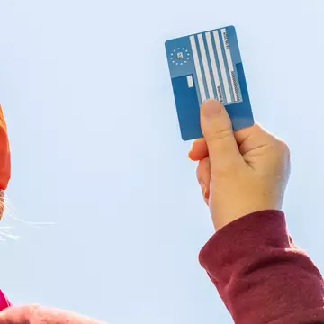 European Health Insurance Card in hand for women. Andrzej Rostek / Shutterstock