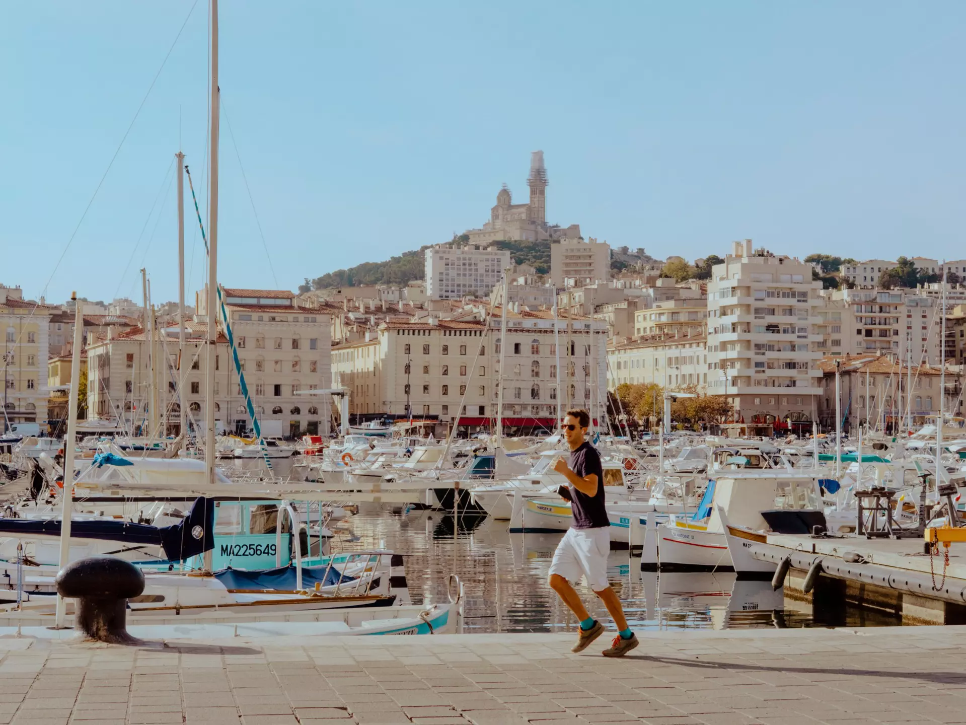 A person on a walkway by a marina with many boats.