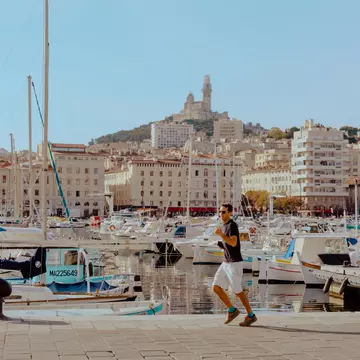 A person on a walkway by a marina with many boats.