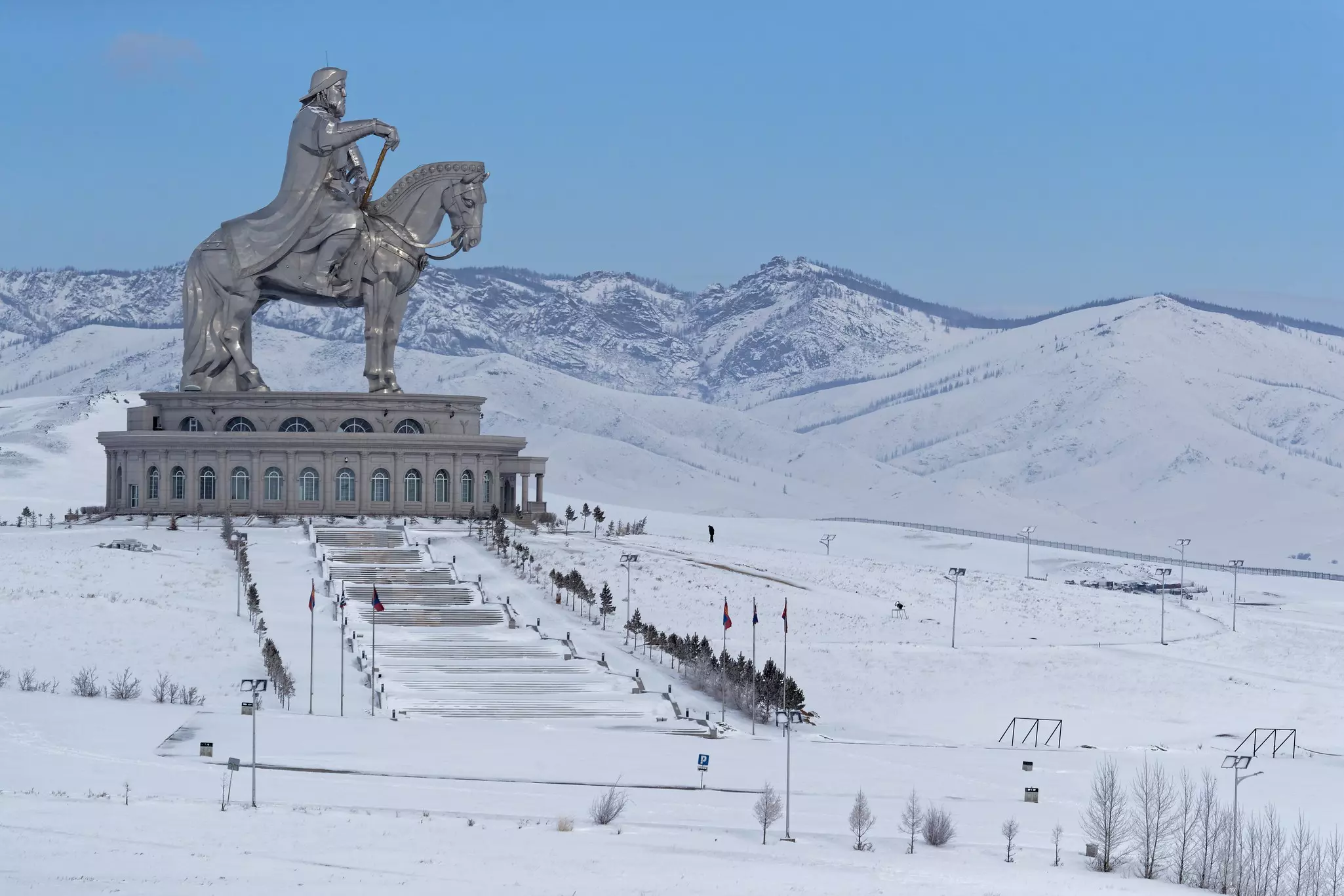 A huge steel statue of a man on horseback towering over a snow-covered hillside.