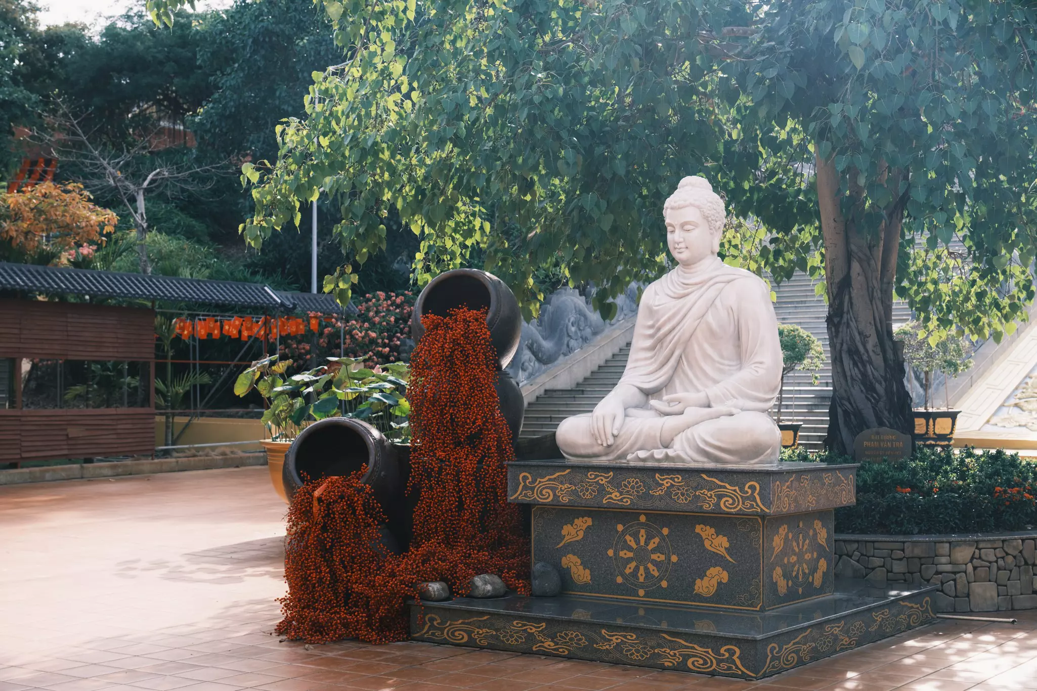 A Buddha statue with engravings surrounded by plants.
