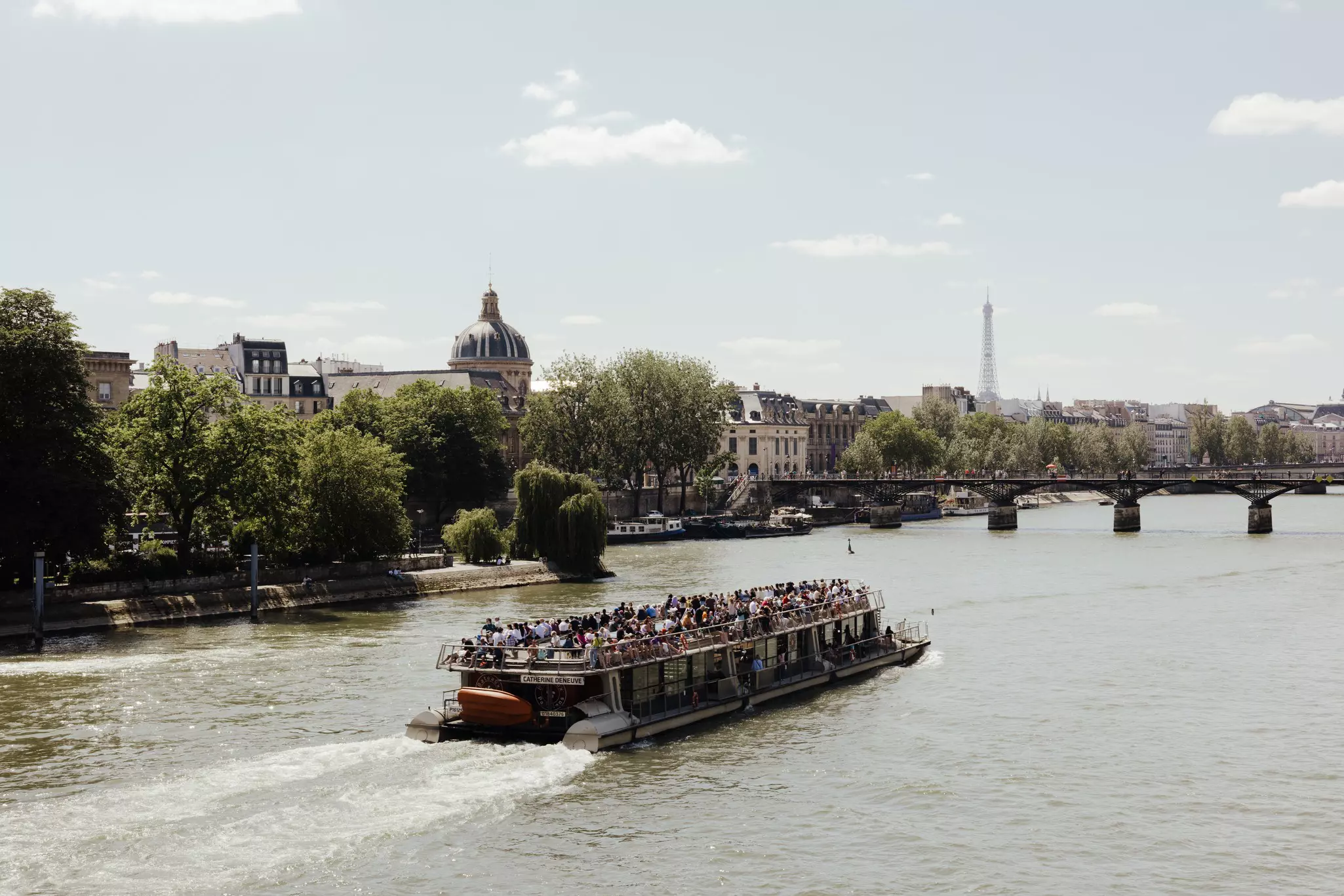 View of a riverboat in the Seine with the Dome of Institut de France and the Eiffel Tower in the background, Paris, France.