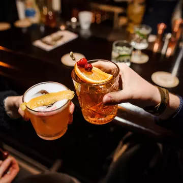 A man and a woman cheersing glasses at a bar counter - a sour mix and Negroni with orange and cherry.
1009098397
alcohol, alcoholic, alcoholic drink, aperitif, are, background, bar, beverage, bitter, campari, cherry, clinking, close up, cocktail, cocktail glass, cold, colorful, cool, counter, drink, fashioned, freshness, gin, glasses, ice, lifestyle, liquid, liquor, man, mix, mixing, mixologist, negroni, orange, party, pouring, preparation, refreshment, restaurant, rum, sitting, sour, sparkling, stirring, woman