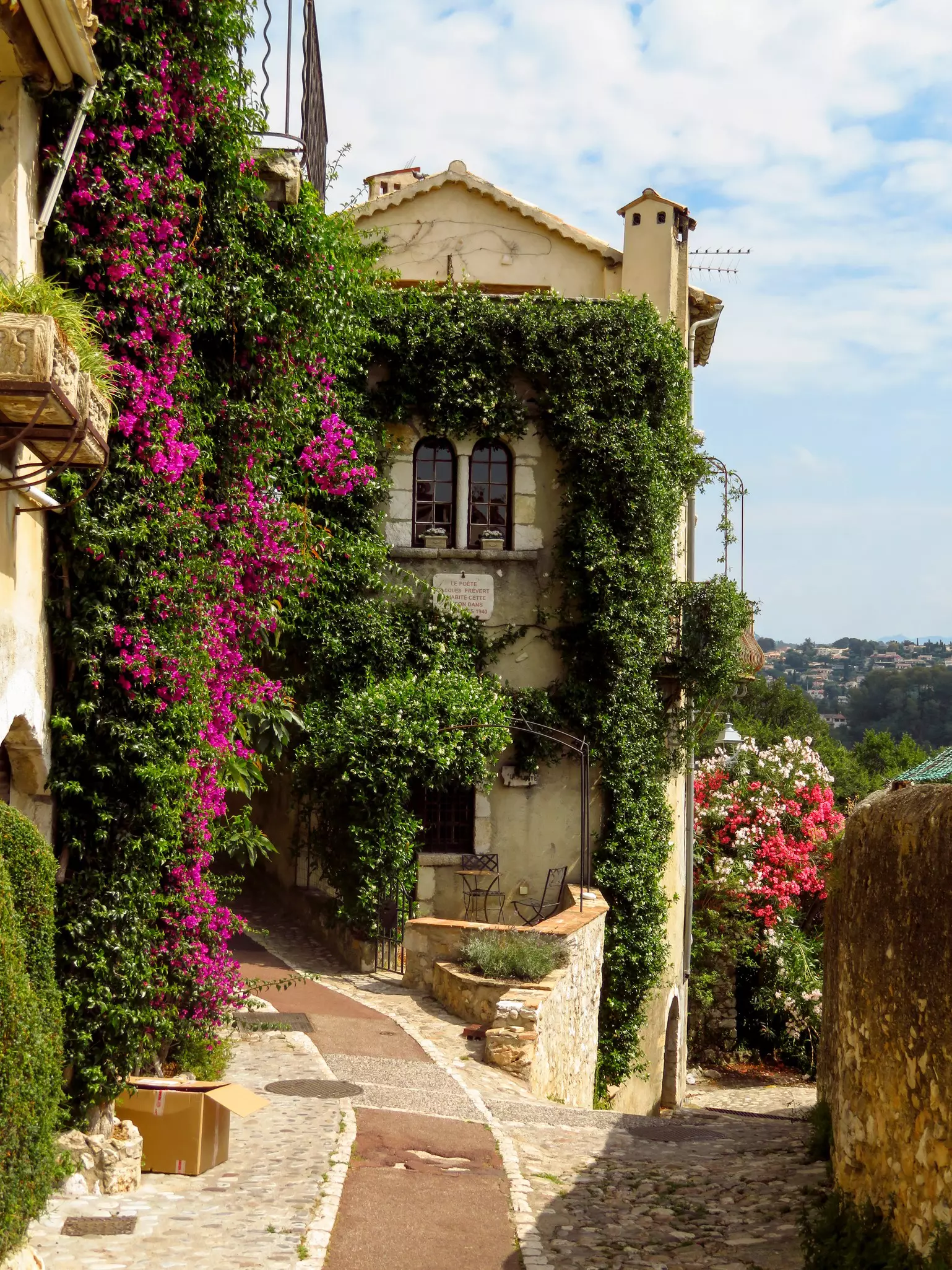 A pretty stone house in a hilltop town covered in plants. 