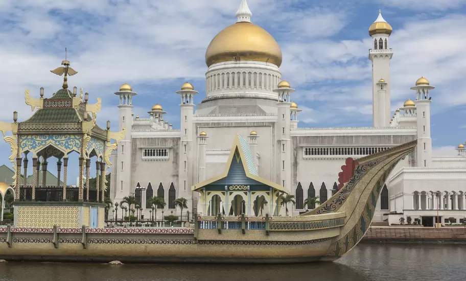 Omar Ali Saifuddien Mosque in Bandar Seri Begawan, Brunei, with its gold dome and minarets behind an ornate stone barge