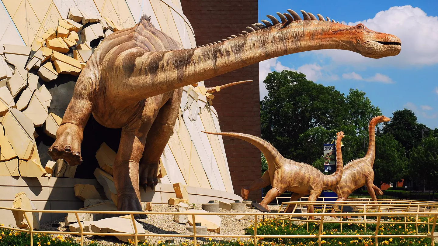 A huge dinosaur model appears to burst through the walls of a building at the children's museum in Indianapolis