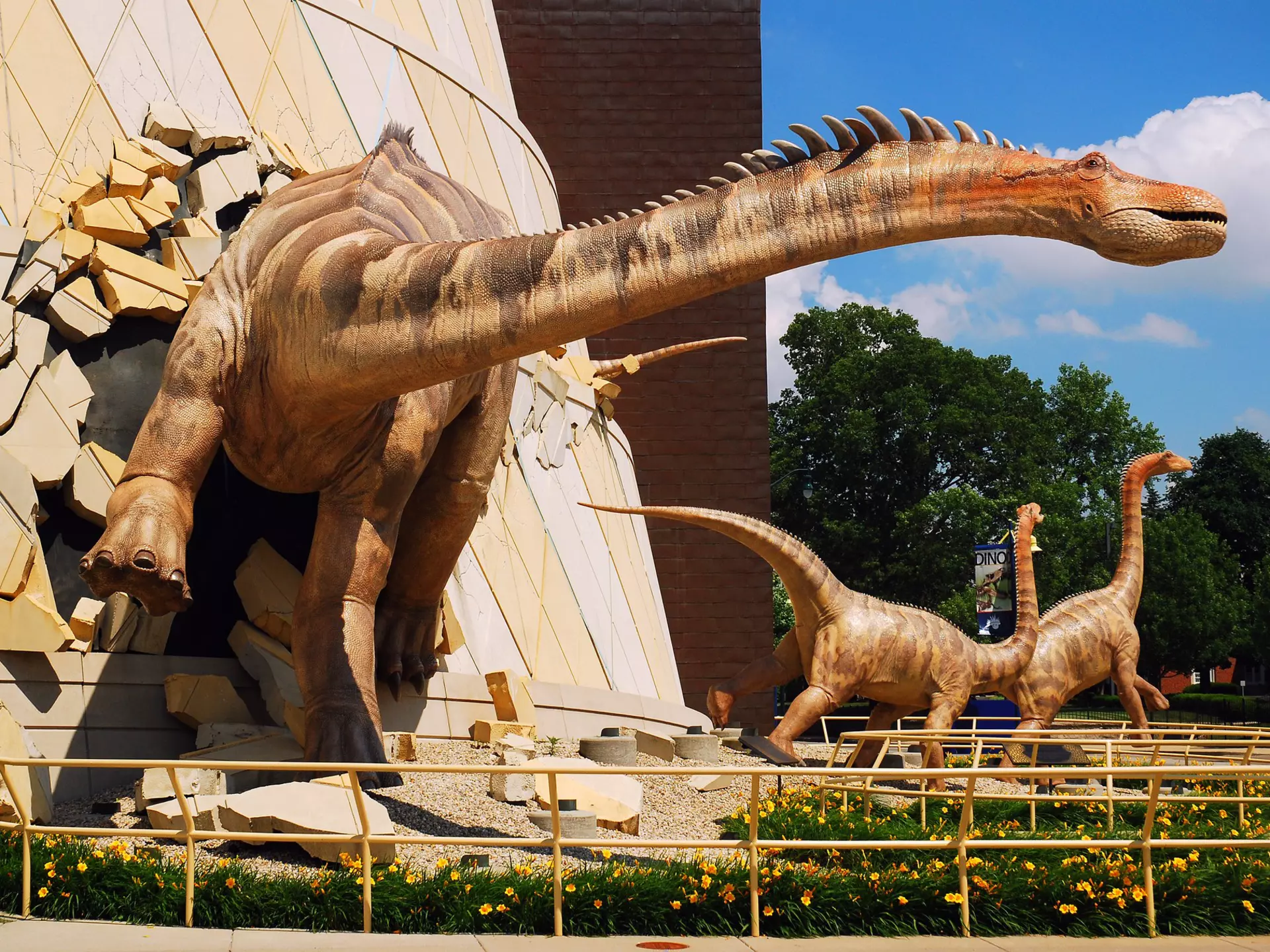 A huge dinosaur model appears to burst through the walls of a building at the children's museum in Indianapolis